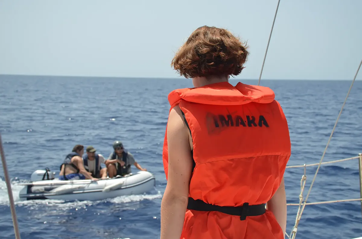 Crewmitglied mit Rettungsweste schaut auf das Dinghy der Imara