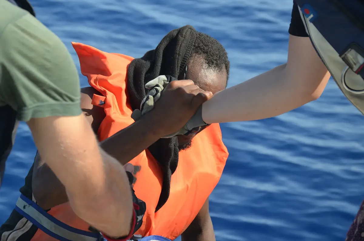 Crewmitglied der Imara hilft geretteten Menschen an Bord